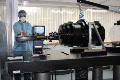 A man stands in front of a lab bench with the APOGEE spectrograph